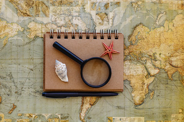 Travel flat lay with notepad magnifying glass and seashells plac
