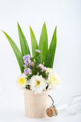 Colorful flowers in the wooden bucket on the white background