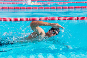 Swimmer man fitness training at swimming pool. Professional male athlete doing crawl freestyle...