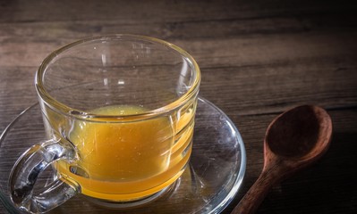 Honey bees in crystal glass with wooden spoon on wooden background.