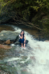 Beautiful young traveling woman enjoy the waterfall.vintage tone hipster style and soft focus.