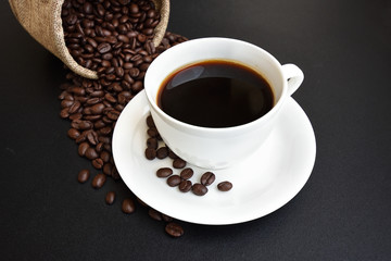 Coffee cup and coffee beans on a dark background.