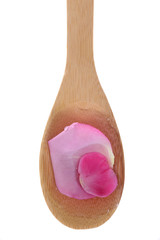 Rose water and rose pedals on a bamboo spoon.