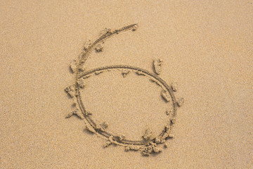 Six number written on sand on summer beach