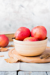 Fresh organic pears in wooden bowl on board on wooden table background. Healthy vegetarian food content.