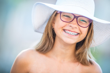 Happy smiling girl with dental braces and glasses. Young cute caucasian blond girl wearing teeth braces and glasses