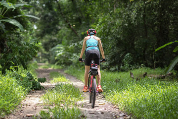 Fototapeta na wymiar woman riding ahead on mountain bike in the rainforest adventure