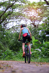 Fototapeta na wymiar woman riding forward mountain bike in the rainforest adventure
