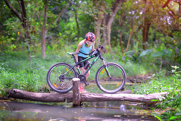 Fototapeta premium woman carry and holding mountain bike cross over the raceway on the timber log