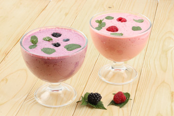 Healthy raspberries and blackberries yogurt with fresh berries on light wooden background