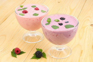 Healthy raspberries and blackberries yogurt with fresh berries on light wooden background