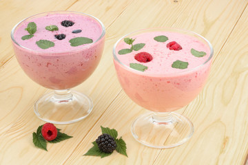 Healthy raspberries and blackberries yogurt with fresh berries on light wooden background