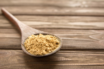 Ginger powder in wooden spoon on wooden table.