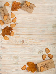 Flat lay frame of yellow leaves, cookies in the form of leaves, hazelnuts and gift boxes on a light wooden background.