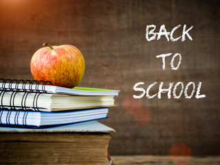 Back to school concept. Retro style of apple on stacks of books on  wooden table background.