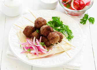 Lamb kebabs on skewers with onion and buttermilk sauce.