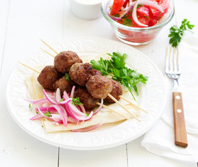 Lamb kebabs on skewers with onion and buttermilk sauce.