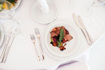 Tasty steak with fried vegetables on table in restaurant on wedding party