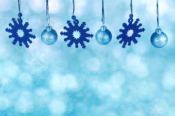 Christmas decoration with blue colored  baubles and snowflakes on light abstract blue background.