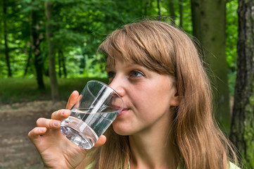 Woman is drinking glass of water at hot summer day