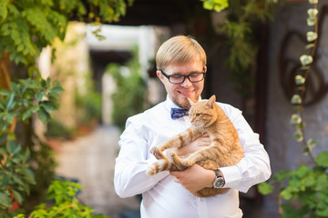 Red cat in the hands of stylish man