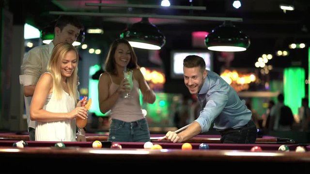 happy young people playing pool billiard
