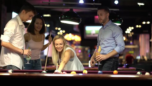 young woman playing billiard with friends doing a good shot cheerful
