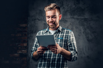 A man holds tablet PC over grey background.