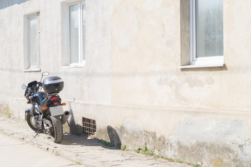 Black motorcycle parked in front of the beige facade of house