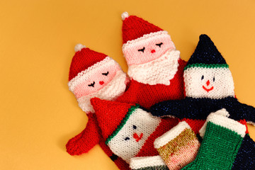 Knitted Father Christmas glove puppets and stockings on a gold background