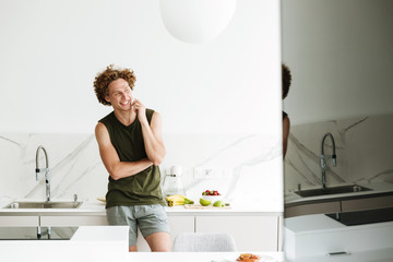 Man standing at the kitchen and talking by phone