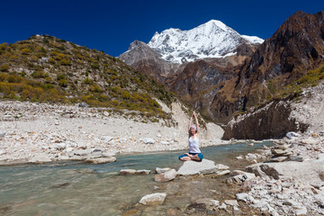 Fototapeta premium Woman is doing yoga excercises near big lake on the Manaslu circuit trak in Nepala