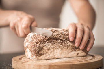 fresh bread in hands closeup on old wooden background