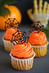 Pumpkin orange cupcakes for Halloween with chocolate cobweb.