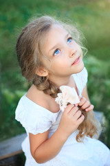 Cute little girl on nature in summer day looking up