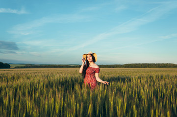 Beautiful young woman at sunset in the field