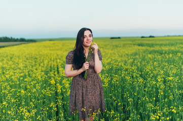 Beautiful young woman at sunset in the field