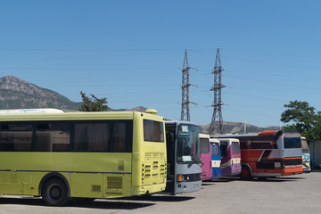 Bus station with colorful buses. Two electric posts on the background.