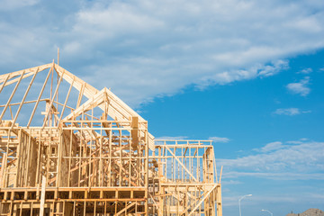 Close-up new stick built home under construction under blue sky in Humble, Texas, US. Framing structure/wood frame of wooden houses/home. House construction and real estate concept background.