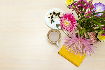 Obraz na płótnie Canvas Перекус с творогом и кофе за столом с астрами в вазе и желтым блокнотом.