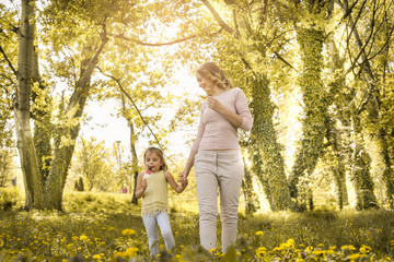 Mother and daughter walking in the meadow and eating ice cream. Happy mother and her daughter enjoying in beautiful spring day.
