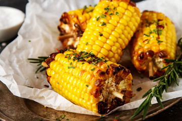 Corn grilled with salt and spices. Dark background. Fast food in