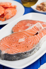 raw salmon, shrimps, nuts and olive oil on wooden background