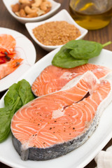 raw salmon, shrimps, nuts and olive oil on wooden background