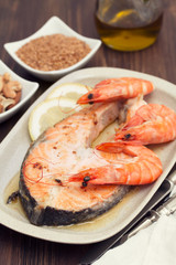 fried salmon with shrimps on white dish on wooden background