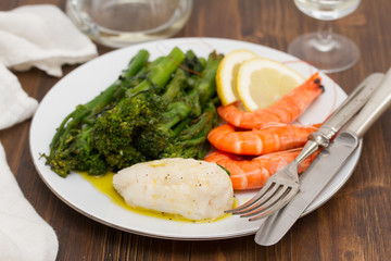 boiled fish with greens and shrimps on white dish