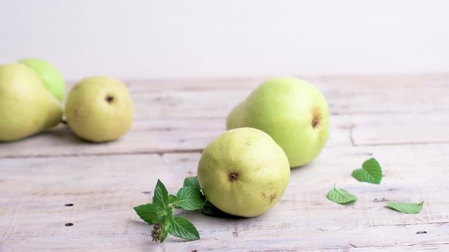 Pears scattered on a white wooden table.