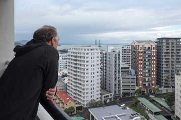 Baby boomer retired man looks at view of apartment buildings in Auckland, New Zealand, NZ © corners74
