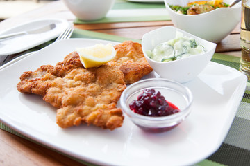Schweineschnitzel Wiener Art mit Preiselbeeren, Gurkensalat und Bratkartoffeln im Restaurant