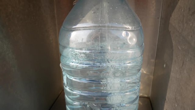 Water flows from the vending machine into a plastic bottle.